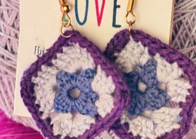 artisan crochet granny square earings made with 100% cotton embroidery thread. Starting with a blue center, then a round of light gry with a purple trim. the findings are hypoallerginic.